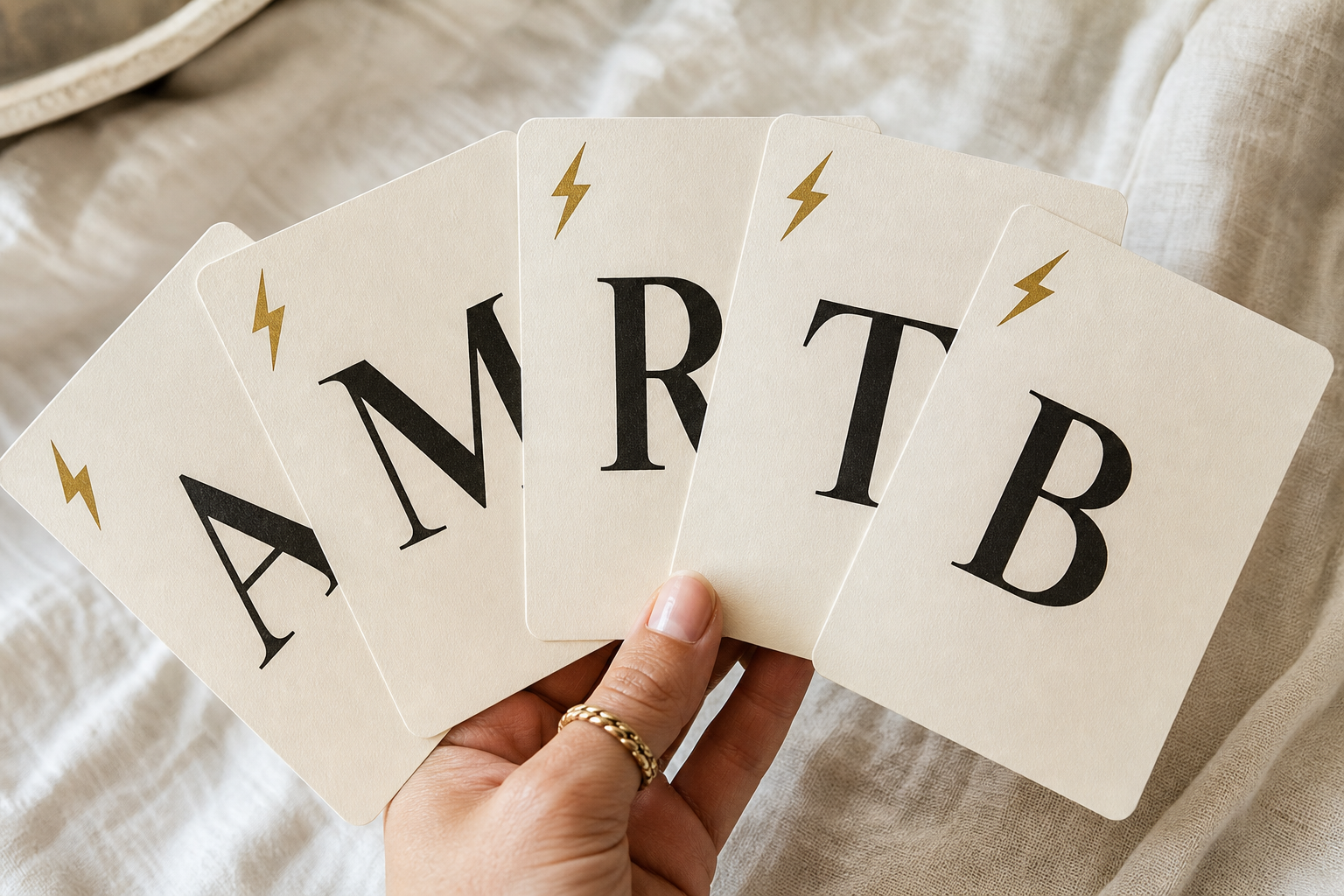 Mano che tiene cinque carte lettera crema con grandi lettere nere e fulmini dorati